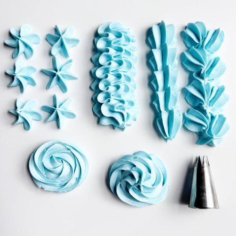 A flat-lay of light blue piped frosting  and a metal 1M piping tip on a white background, showing star, ruffle, rosette, and swirl patterns.