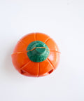 The top view of a 3d orange pumpkin-shaped chocolate with a green stem photographed on a plain white background.