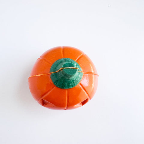 The top view of a 3d orange pumpkin-shaped chocolate with a green stem photographed on a plain white background.