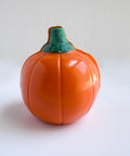 The back side of a 3d orange pumpkin-shaped chocolate photographed on a white background.