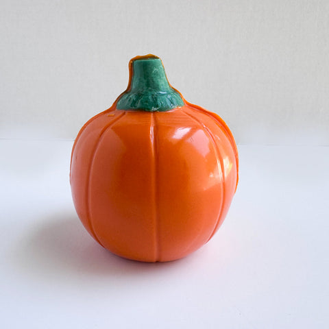 The back side of a 3d orange pumpkin-shaped chocolate photographed on a white background.