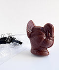 dark chocolate molded turkey with the mold used to make it to the left of it along with the binder clips that were used to secure the mold.