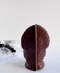 the back side of a 3d dark chocolate molded turkey and the mold used to make it sitting to the left along with the binder clips used to secure the mold when using it.