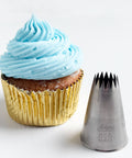 6B french star piping tip also known as Ateco tip 866 next to a light blue swirled frosting cupcake in a gold foil cupcake liner.