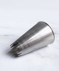 6B ateco tip 866 french star pastry tip laying on it's side on a white background.