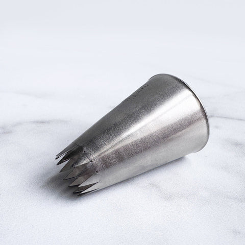 6B ateco tip 866 french star pastry tip laying on it's side on a white background.