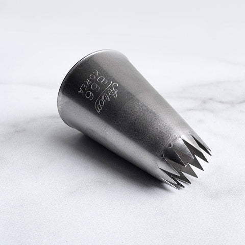 6B french star piping tip also known as Ateco 866 pastry tip laying on it's side on a white background.