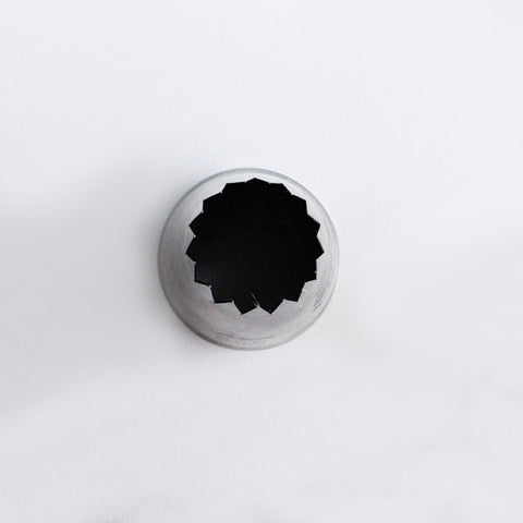 Over head shop of  the 6B pastry tip or piping nozzle with a dark star-shaped opening, photographed from above on a clean white background.
