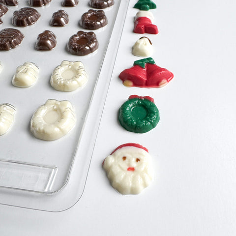 Decorative chocolate molds with shaped chocolates on a white background