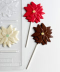 Chocolate poinsettia lollipops next to the plastic candy mold to make them.