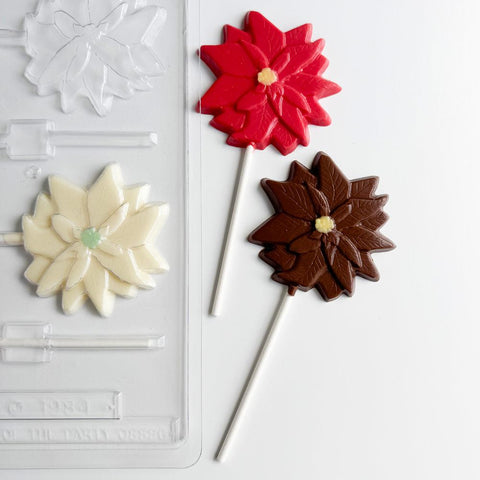 Chocolate poinsettia lollipops next to the plastic candy mold to make them.