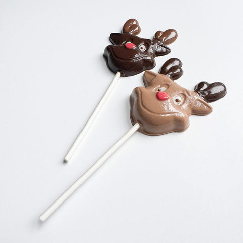 Two chocolate reindeer lollipops on white sticks against a light gray background