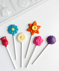 Colorful flower-shaped lollipops on sticks with plastic candy mold