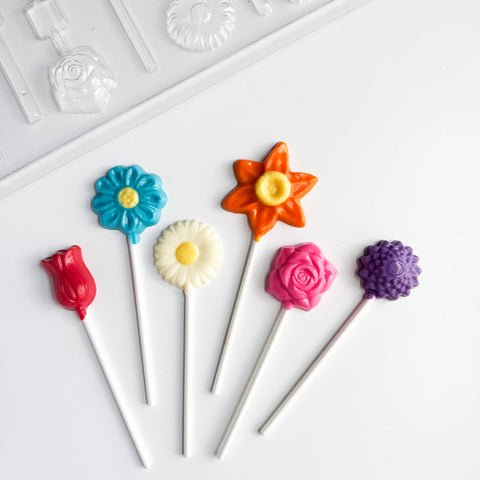 Colorful flower-shaped lollipops on sticks with plastic candy mold