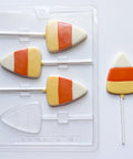 A clear plastic candy corn lollipop mold with three filled candy corn lollipops and a separate candy corn lollipop on a white background.