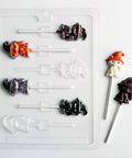 cat with witch or wizard hat shaped chocolate mold for making cat shaped lollipops for Halloween. A clear plastic mold along side two cat shaped lollipops in white chocolate with an orange chocolate hat and the other lollipop made with dark chocolate.