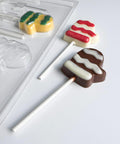 Mitten shaped lollipops along side plastic candy mold