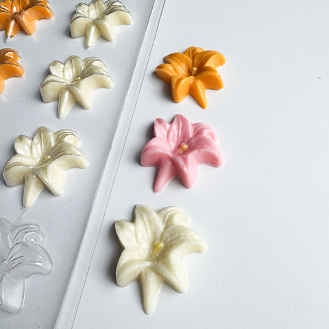 Easter lily shaped chocolates along side the plastic candy mold for making them.
