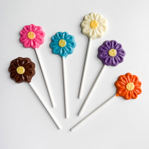 Colorful flower-shaped lollipops on sticks against a white background