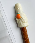 Pretzel rod with white chocolate ghost holding an orange pumpkin.