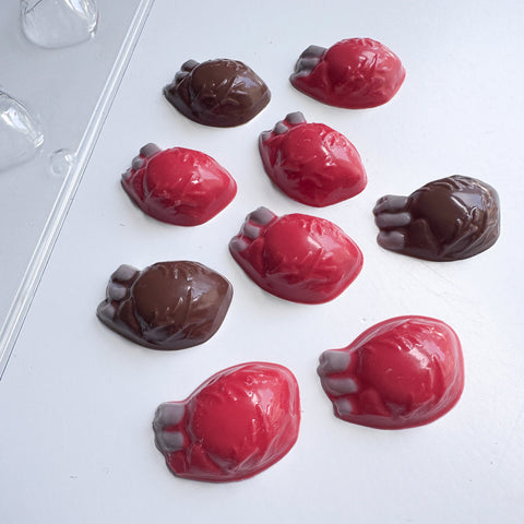 Nine glossy, anatomically shaped chocolate hearts in red and dark brown, arranged on a clean white surface.