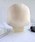 The back side of a 3d skull made from white chocolate next to the clear mold and binder clips used to make it.