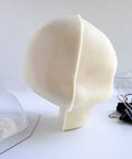 the side view of a white chocolate skull next to the chocolate molds and binder clips used to make it.