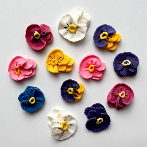 assortment of colorful mini pansy royal icing decorations.