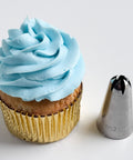 2d metal piping tip also labeled ateco tip 852 next to a cupcake with blue frosting, a gold foil cupcake liner, and a ruffled swirl.