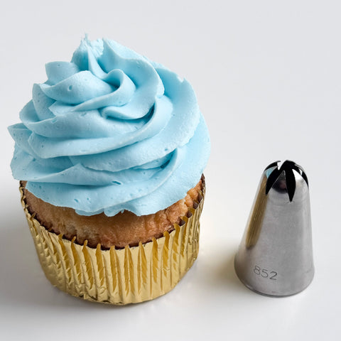 2d metal piping tip also labeled ateco tip 852 next to a cupcake with blue frosting, a gold foil cupcake liner, and a ruffled swirl.