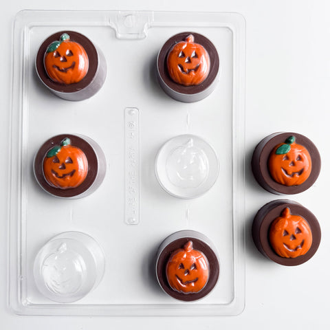 Six Halloween-themed chocolate covered sandwich cookies with jack-o'-lantern faces in orange and brown, shown with the sandwich cookie plastic candy mold used to make them.