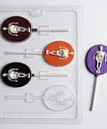 oval lollipop chocolate mold with skeleton in the center. One finished skeleton lollipop to the right of the plastic mold, made with purple chocolate for the oval part and the skeleton is made in white chocolate.