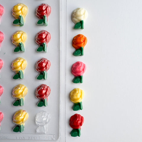 small rose chocolate pieces  with plastic candy mold in the background