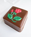 box made of chocolate with rose on the cover along side the plastic mold to make it