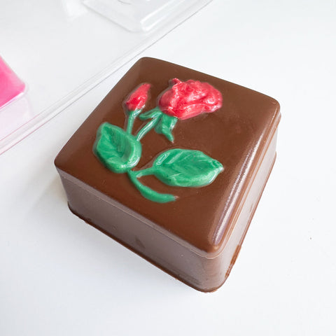 box made of chocolate with rose on the cover along side the plastic mold to make it