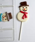 Smiling snowman lollipop made of chocolate next to plastic chocolate mold