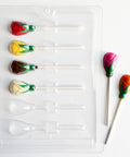 plastic chocolate mold that makes small tea rose lollipops, along side tea rose lollipops made of chocolate.