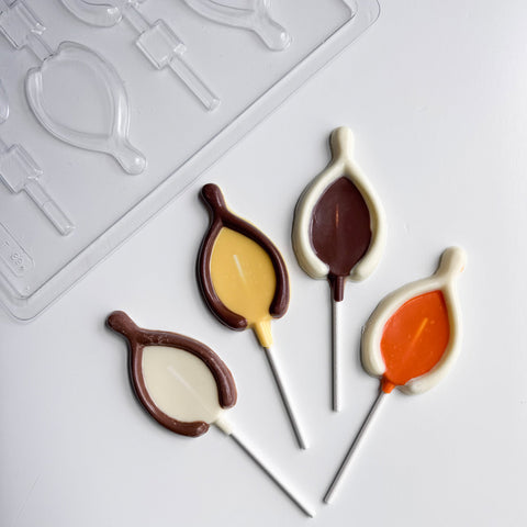 Wishbone shaped chocolate lollipops for Thanksgiving shown along side the finished chocolate lollipops made with milk, white, yellow, and orange chocolate.